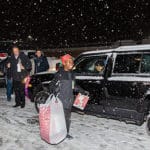 A happy boy carries a large bag of gifts to his car