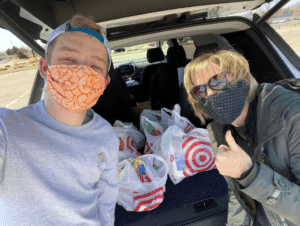 photo of a man and woman wearing masks with a trunkful o groceries
